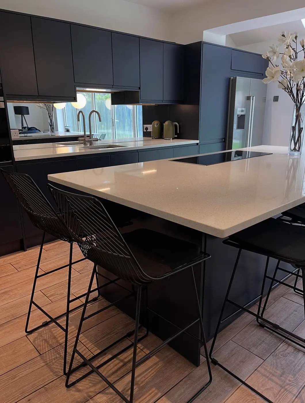 Navy kitchen island with quartz worktop and wire bar stools
