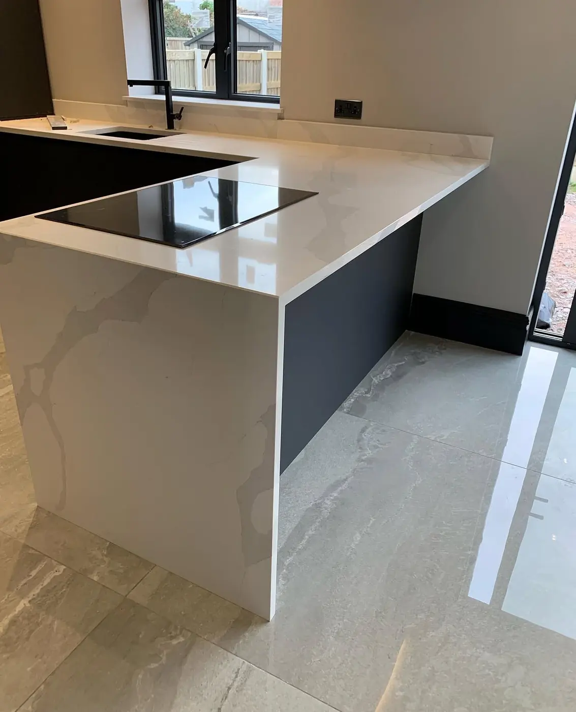 Quartz waterfall-edge peninsula with flush induction hob