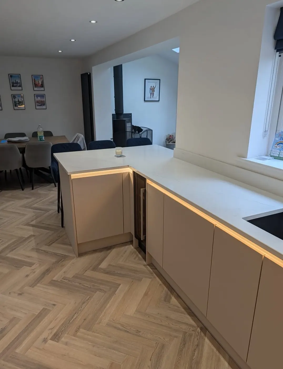 Cashmere kitchen peninsula with plinth lighting on herringbone flooring